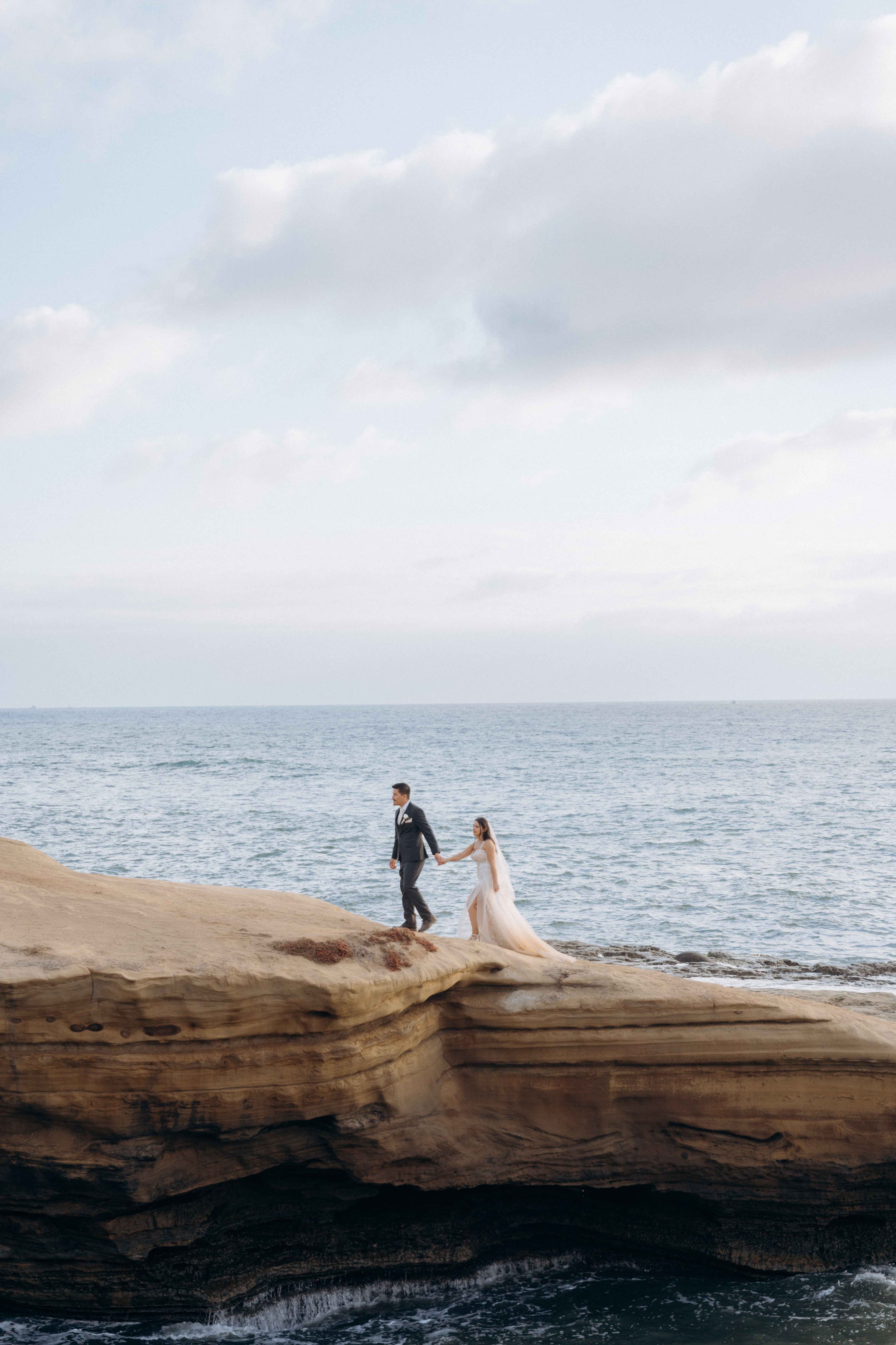 Couple walking on dramatic cliff overlooking the ocean